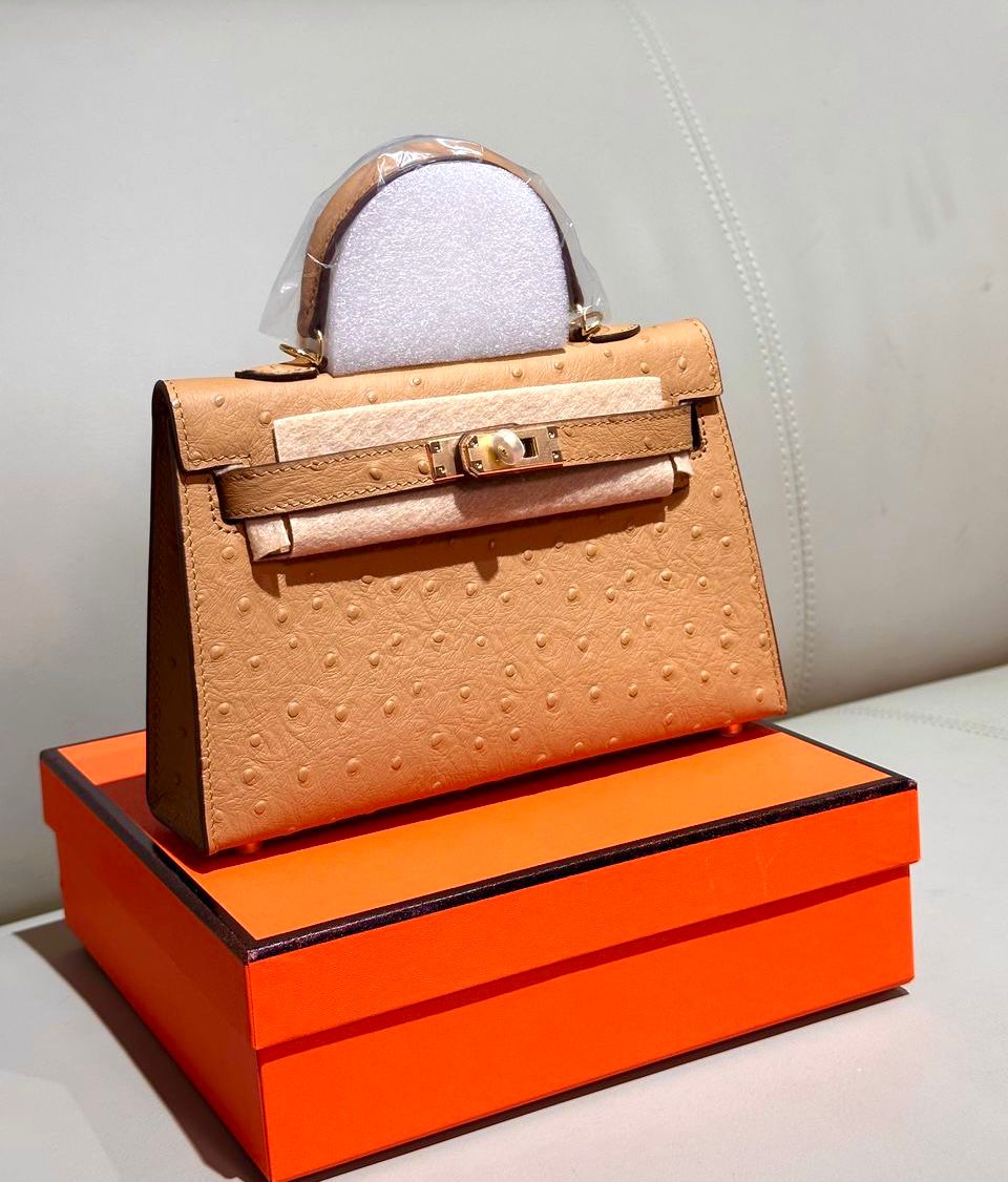 Herm?s Kelly mini bag made from ostrich leather, possibly in a beige or gold color, with gold-toned hardware. image 1