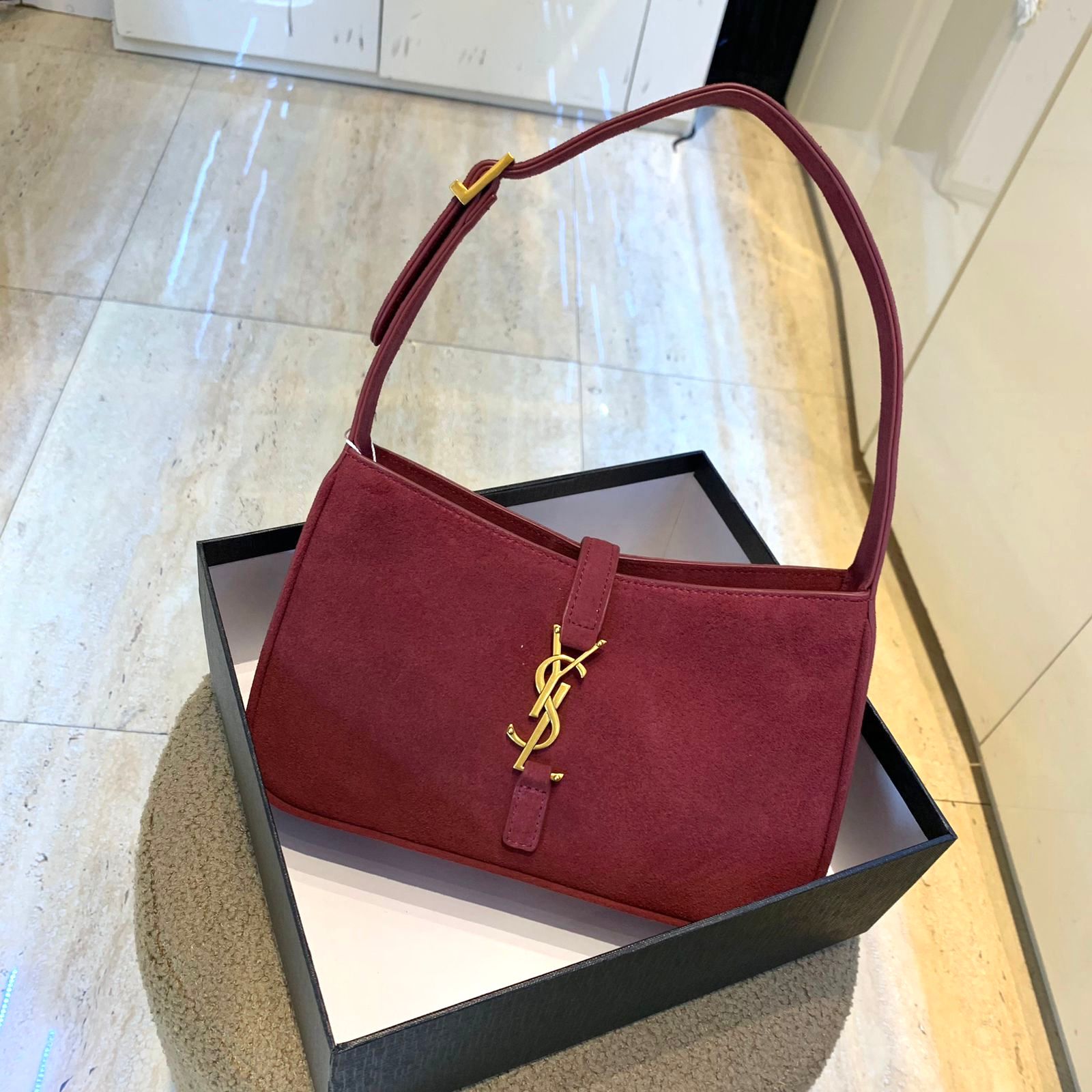 Saint Laurent Le 5 ? 7 hobo bag in a burgundy suede material with a gold-tone YSL logo hook closure. image 1