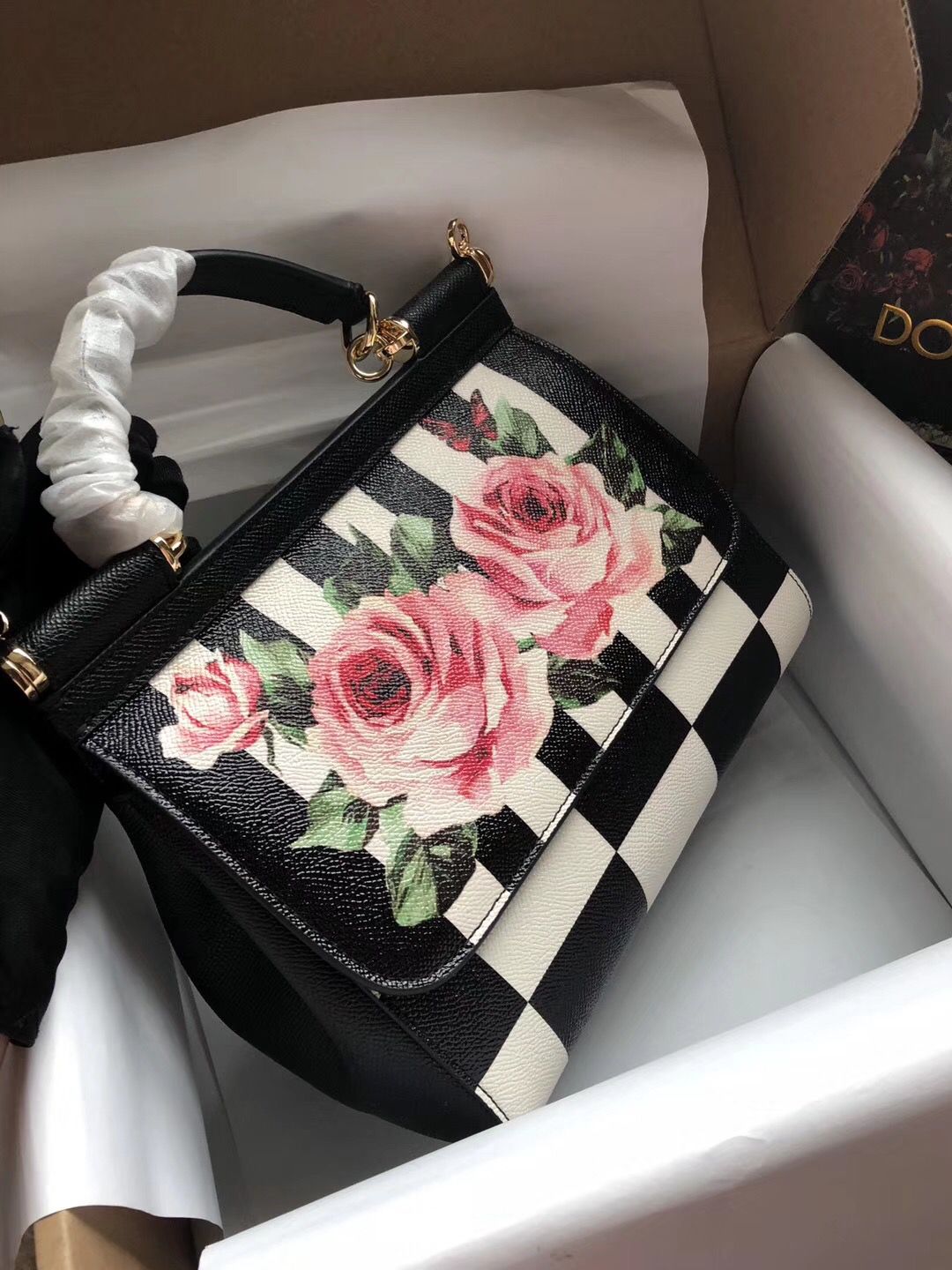 Dolce & Gabbana Sicily top-handle bag featuring a black and white striped and checkered dauphine leather design with a pink rose print. image 1