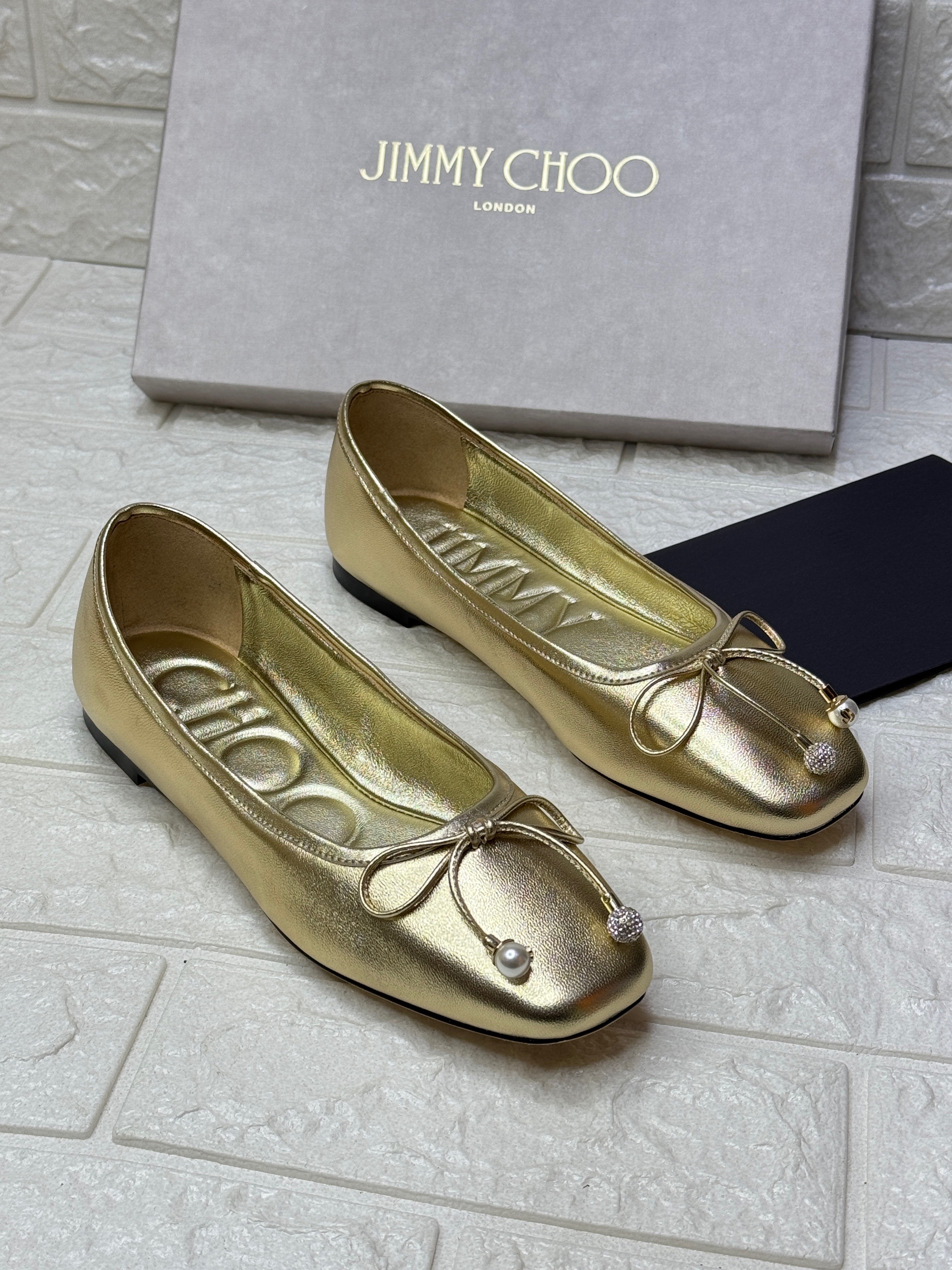 Jimmy Choo Elme metallic nappa leather ballet flats in gold, featuring a square toe and a bow with a crystal and pearl embellishment. image 1
