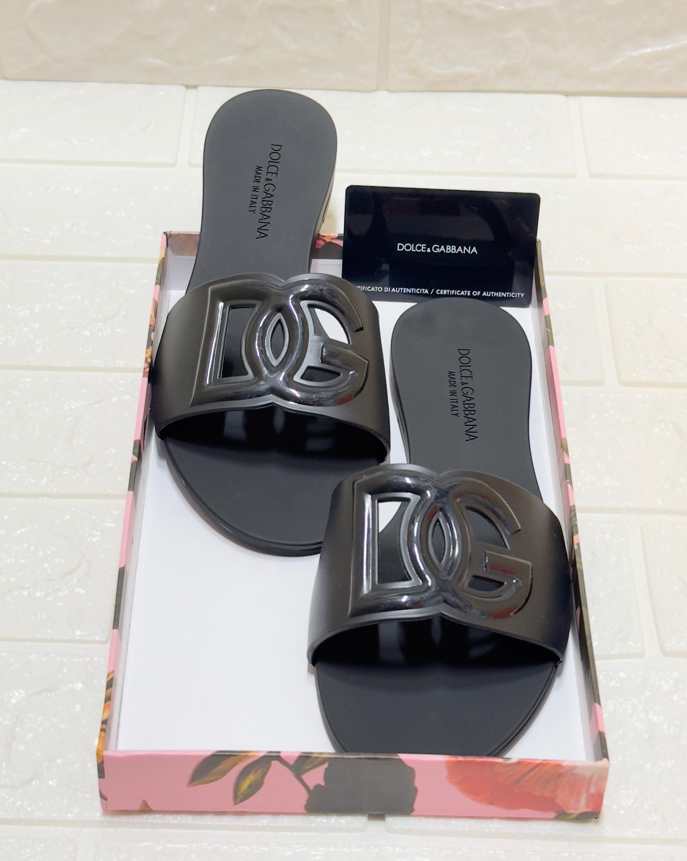 Dolce & Gabbana DG logo rubber beachwear slides in black. They feature a cut-out DG logo detail on the strap, a branded rubber sole, and are made in Italy from durable rubber image 1