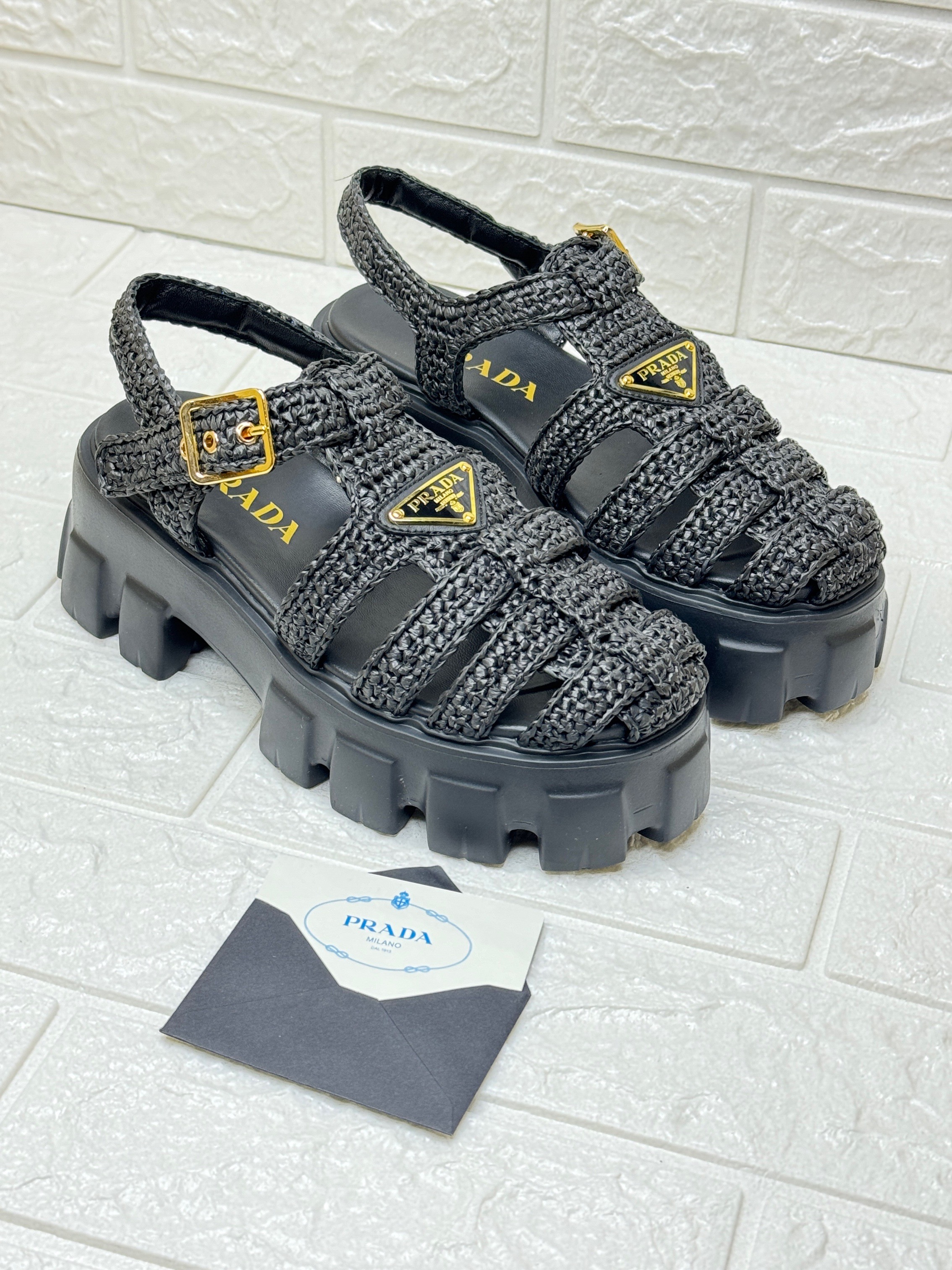 Prada Monolith Crochet Cage Sandals in black, featuring a raffia-effect yarn upper and a chunky rubber lug sole with gold-tone hardware. image 1