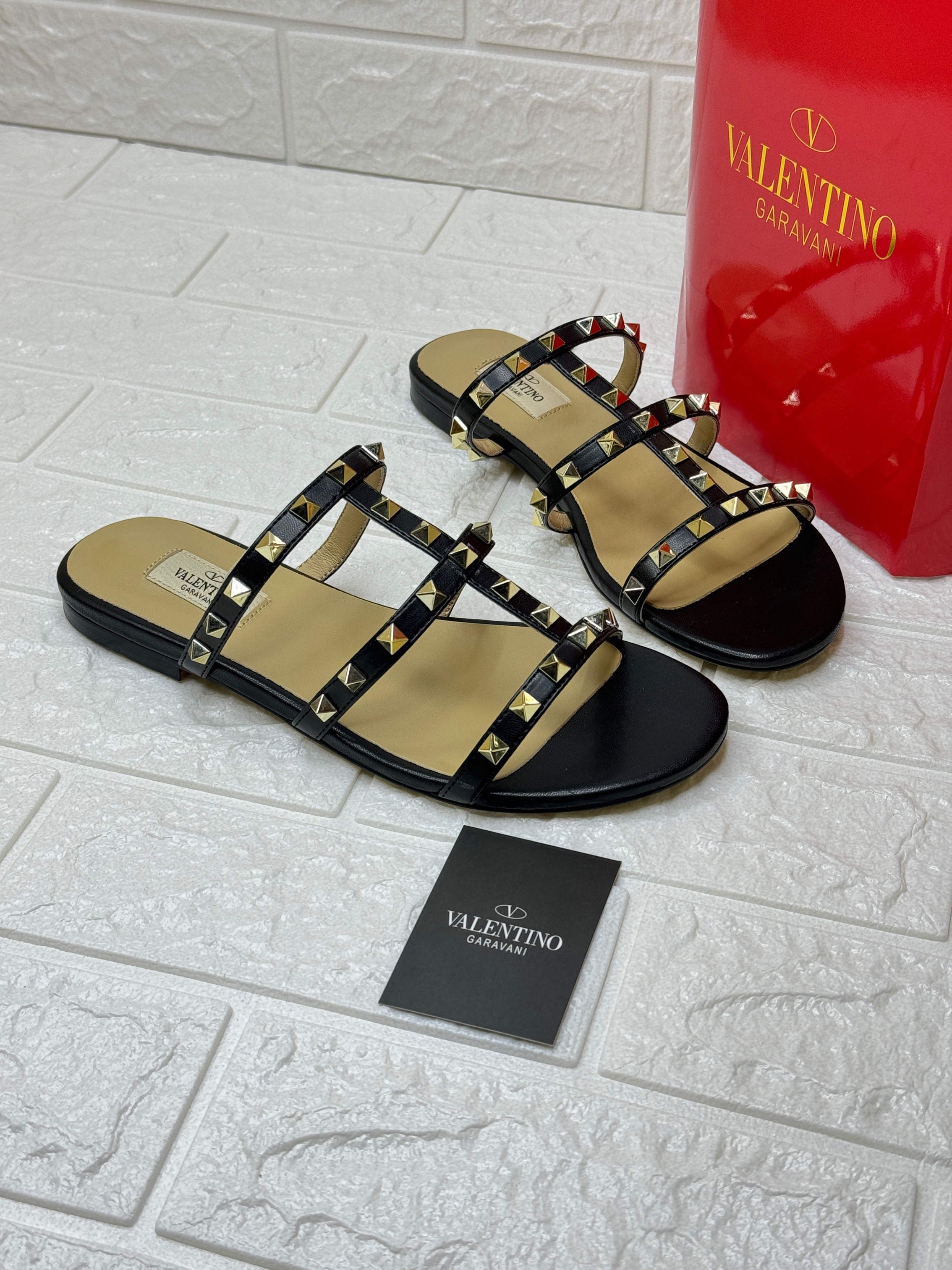 Valentino Garavani Rockstud flat leather slide sandals in black with gold-tone pyramid studs. image 1