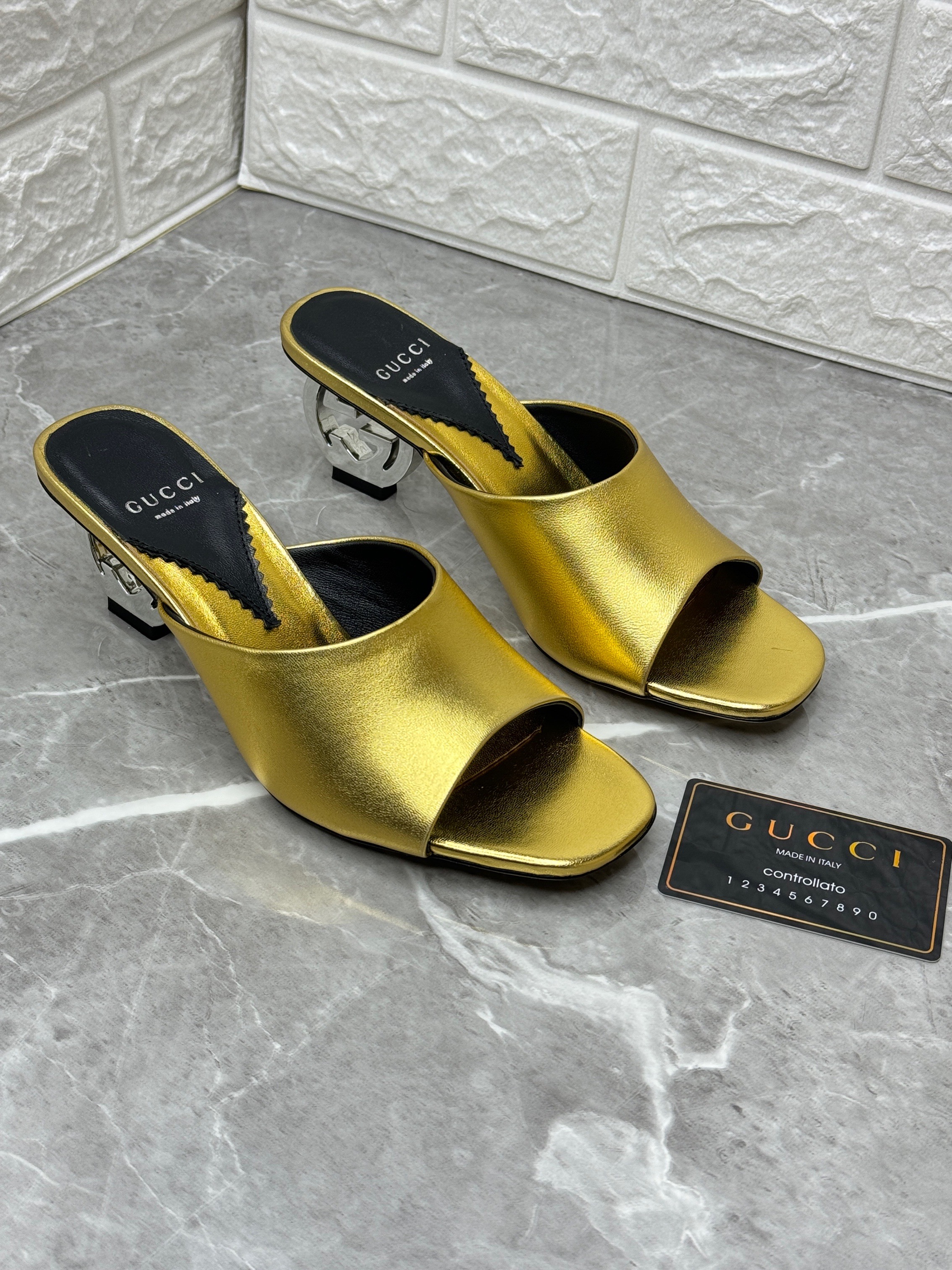 Gucci Bella GG Heel Slide Sandals in metallic gold leather, featuring an interlocking GG logo as the clear heel. image 1