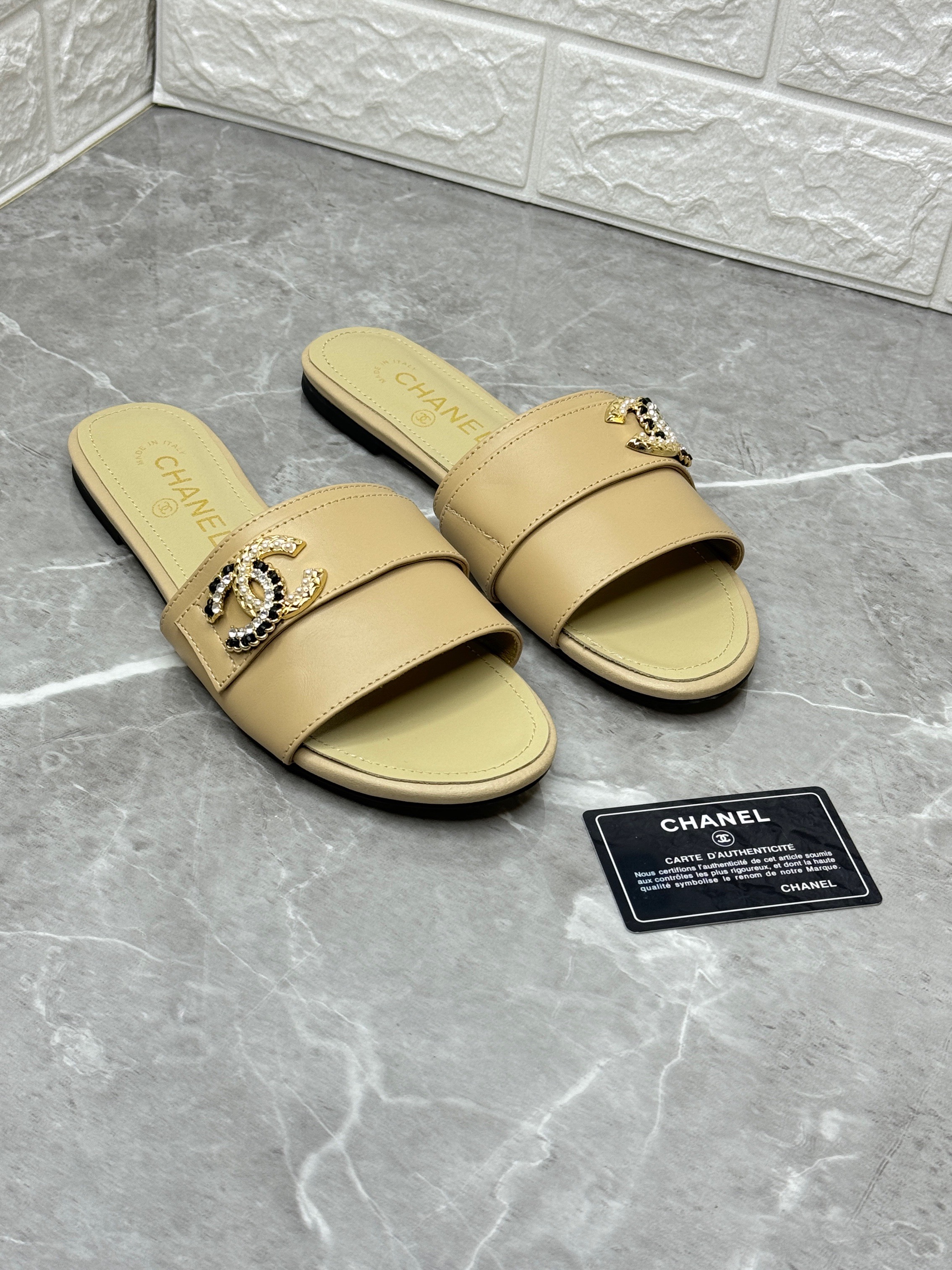 Chanel slide sandals in a beige or tan leather with an embellished CC logo on the front strap. image 1