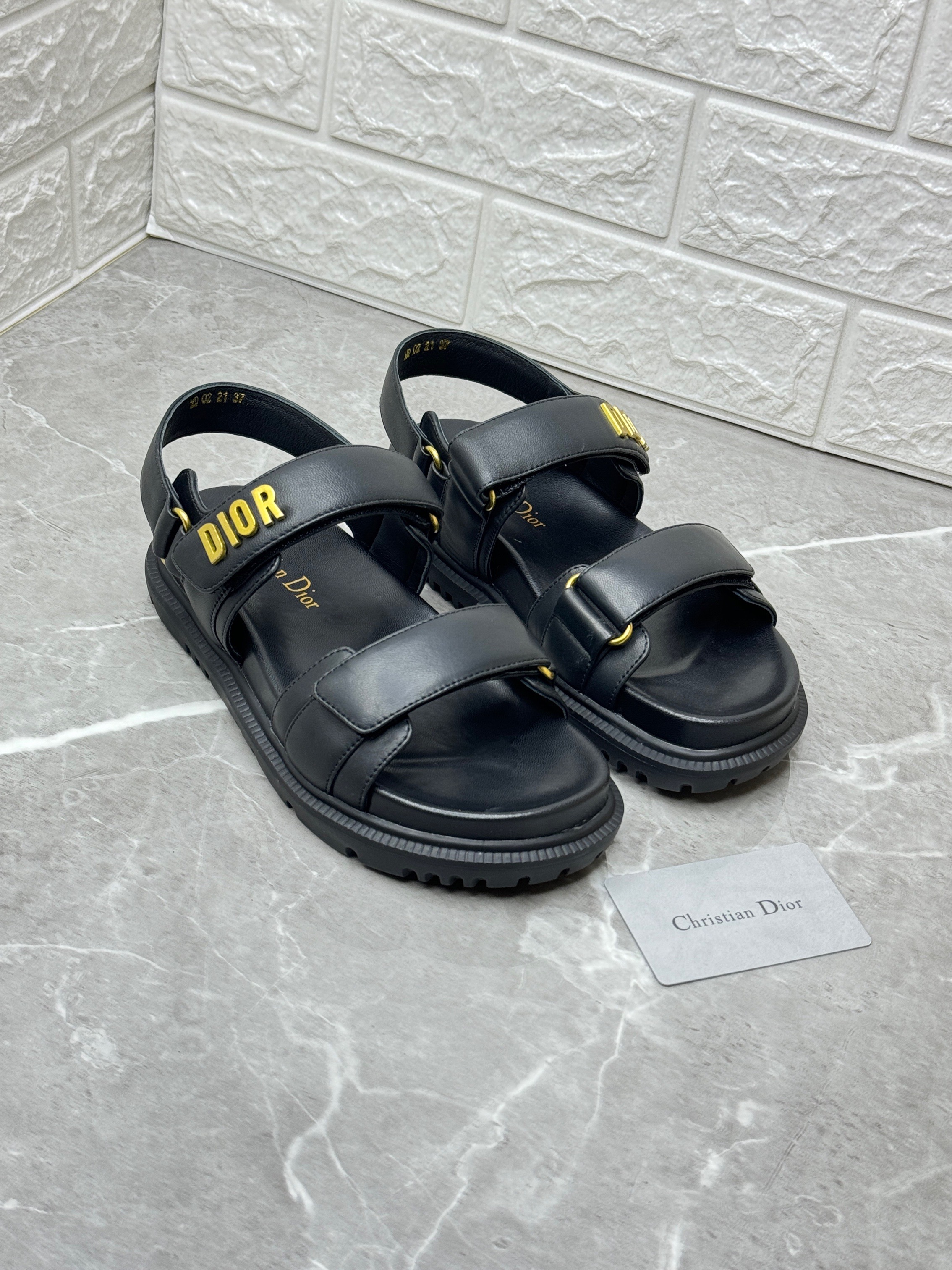 Dior Dioract sandal in black lambskin leather with a gold-finish metal Dior signature on the upper band. image 1