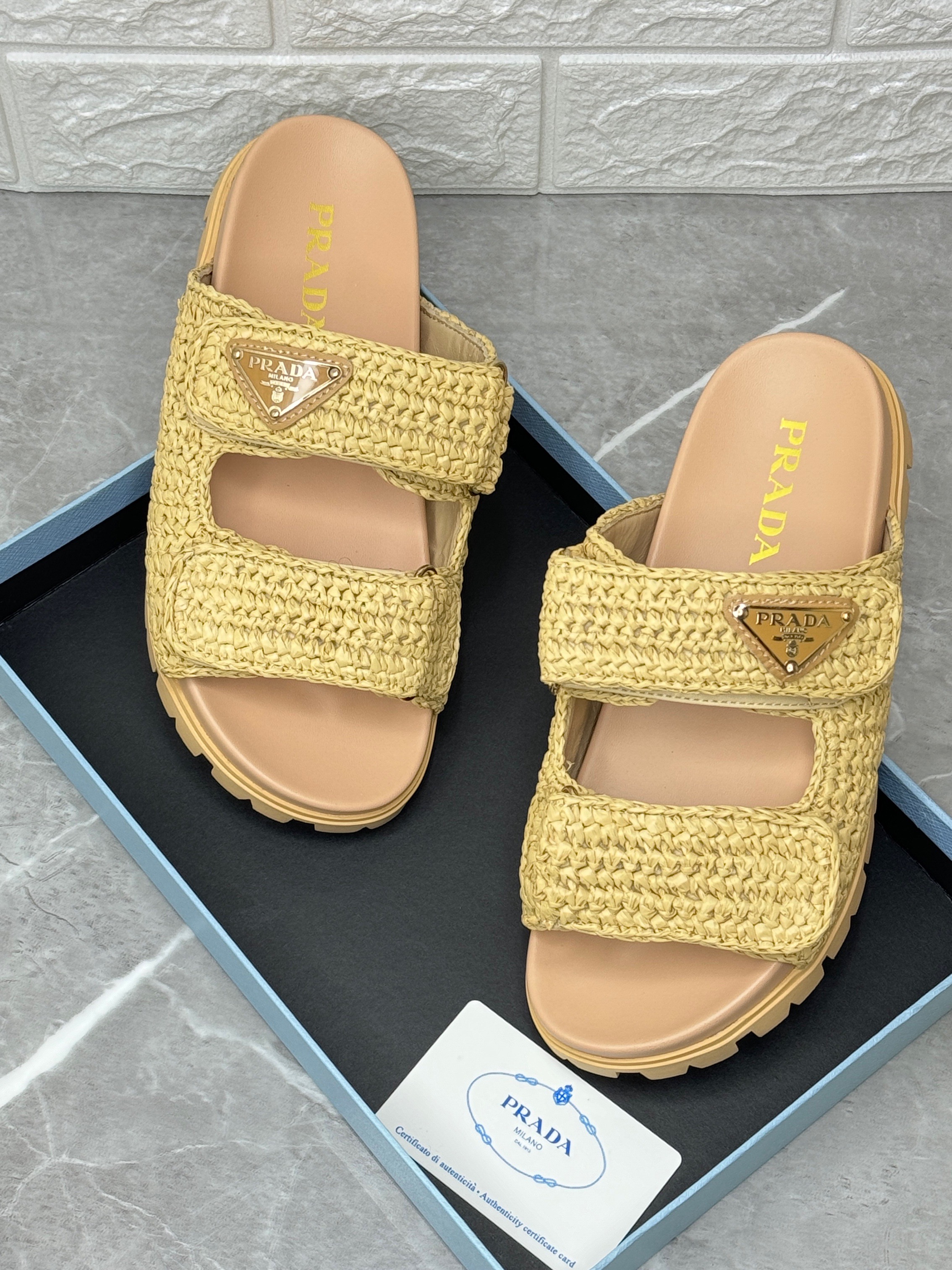 Prada Fussbett Raffia Dual Buckle Slide Sandals in a natural or beige color. image 1