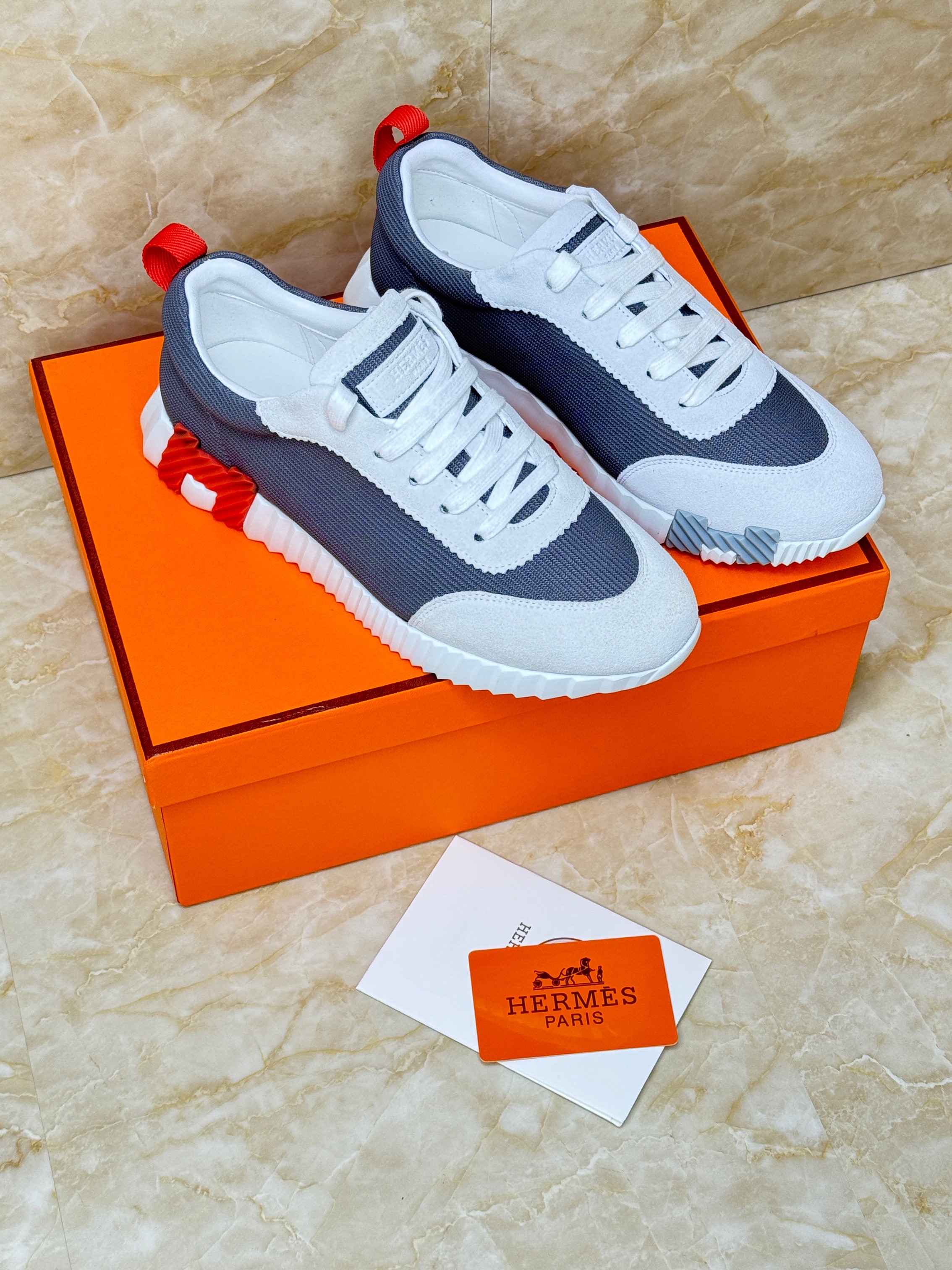 Herm?s Bouncing sneakers in technical mesh and suede goatskin, in the white and navy blue colorway with orange accents. image 1