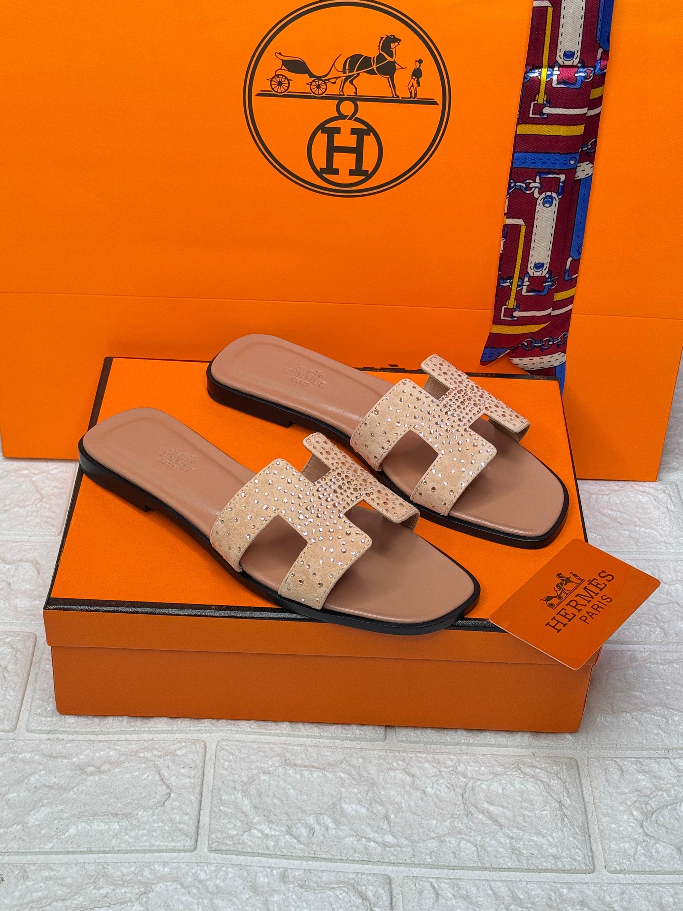 Herm?s Oran sandals in a light beige or off-white color with an "H" cut-out strap and studded embellishments. image 1